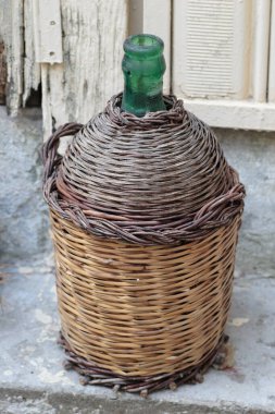 Duvara yaslanmış yaşlı Demijohn Wicker