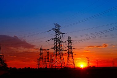 Elektrik kuleleri, günbatımında endüstriyel enerji tesisleri