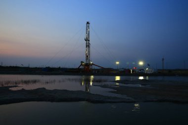 Geceleri rafinerinin arka planında petrol sondaj platformu. 