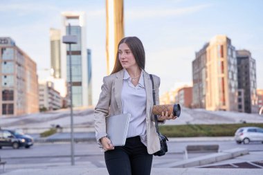 Genç öğrenci dizüstü bilgisayarıyla yürüyor.