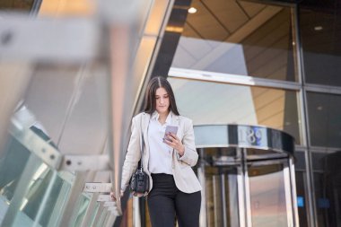 Ofis binasının dışında akıllı telefonunu kullanan bir kadın.