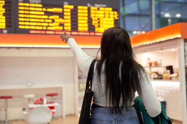 Genç Afro-Amerikalı kız uçuş bilgileri ekranına bakıyor.