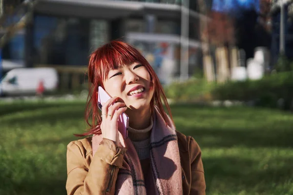 Genç Asyalı kadın bir telefon görüşmesi yapar, cep telefonuyla konuşur ve sokakta yürür.