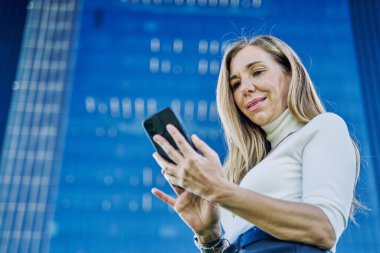 Başarılı bir orta yaşlı yönetici akıllı telefonuyla işini her yerden yönetiyor. Dijital çağda verimlilik kavramı..