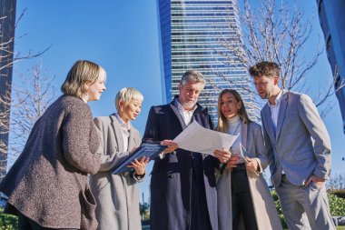 Bir grup işadamı bina planına bakarken yürüyorlar. bir projeyi tartışan mimarlar.