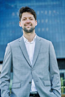 Takım elbiseli bir iş adamının portresi kameraya liderlik ve gülümsemeyle bakıyor.