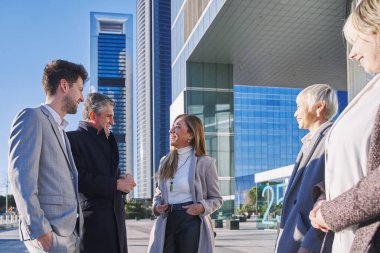 Ofis binalarının önünde bir grup iş arkadaşı iş planını tartışıyor..