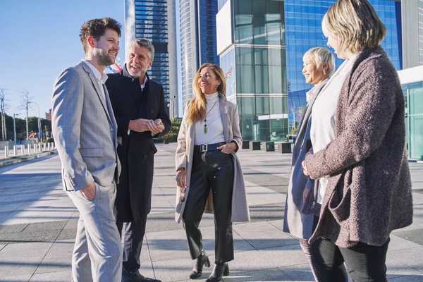 Ofis binalarının önünde bir grup iş arkadaşı iş planını tartışıyor..