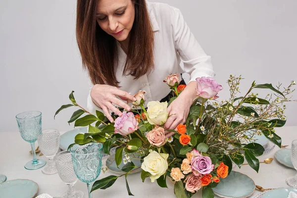 Tanımlanamayan bir kadın çiçekleri bir etkinlik masasına hazırlıyor.