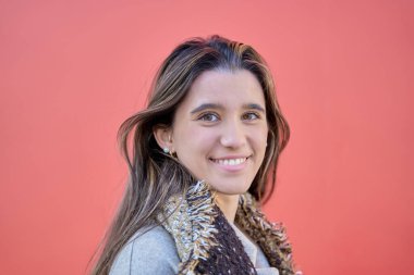 Kırmızı arka planda beyaz dişlerini gösteren genç bir kadının portresi.