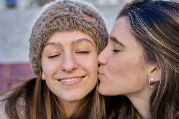 young teenager kissing her friend or sister with affection and emotion. woman kissing her best friend.