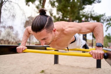 Üstsüz genç bir adam şınav çekiyor.