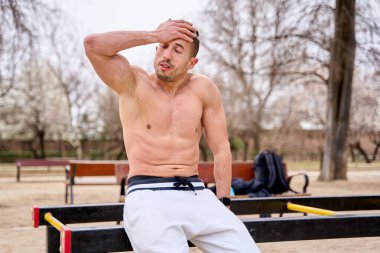 Üstsüz adam sıkı bir çalışmadan sonra dinleniyor.