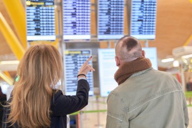 Kadın ekranı gösterirken çift uçuş bilgilerini ekranda kontrol ediyor