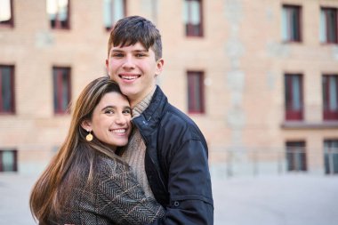 Genç çift gülümseyerek kameraya bakıyor. Metin için kopyalama alanı olan kucaklayan bir çiftin portresi.