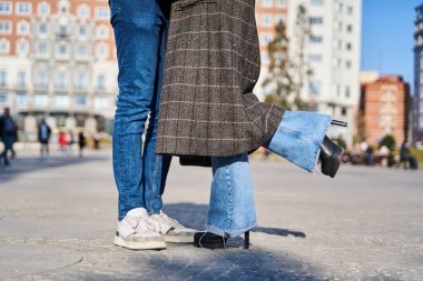 Şehirde yürüyüş yapan romantik bir çiftin detayları. Şehirde birbirini kucaklayan bir çiftin yan görüntüsü.