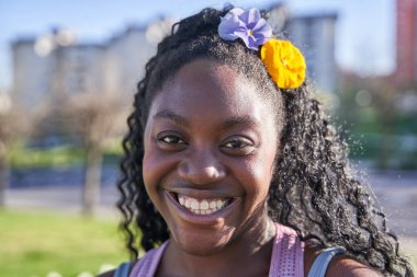 Saçında çiçeklerle gülümseyen Afrikalı Amerikalı bir kızın portresi..