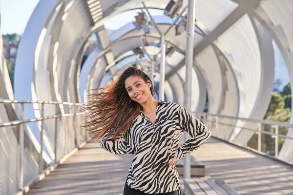 portrait of a young latina woman looking at the camera with her hair blowing in the wind