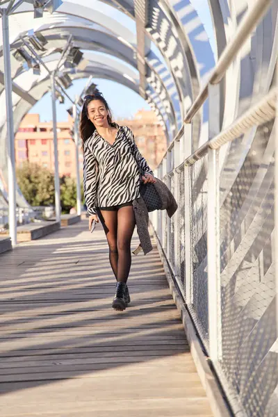 full view of a stylish young latina walking. Smiling brunette woman
