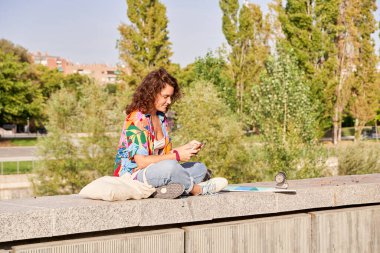 Dışarıda akıllı telefonlara bakan kaykaylı genç şehir kızı. Cep telefonu kullanan kaykaylı mutlu genç hippi kadın.