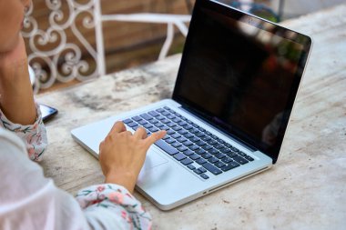 Dizüstü bilgisayarını kullanan genç bir öğrencinin ellerinin detayları.