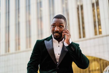 Genç işadamı ofis dışında akıllı telefondan konuşuyor.