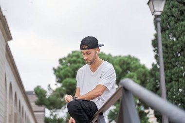 Yakışıklı genç adam şehirde oturuyor ve akıllı bakışlarına bakıyor.