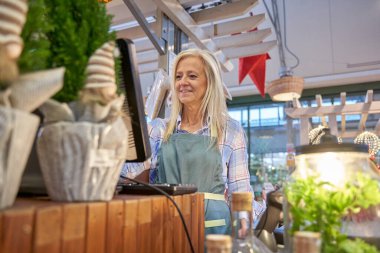 Dükkanda çalışan kasiyer gülümsüyor.