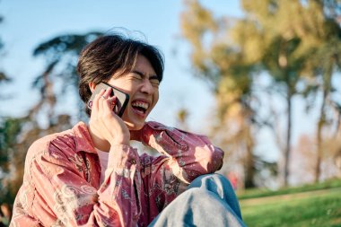 Akıllı bir telefonla konuşan Asyalı genç bir adamın portresi.