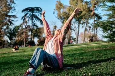 Genç Asyalı adam kolunu kaldırıyor ve dışarıda temiz hava soluyor..