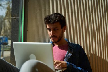 Bilgisayarını kullanarak oturan sakallı bir adamın yakın plan portresi.