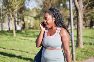 Afro-Amerikan kadın akıllı telefondan konuşuyor.