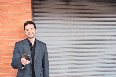 Gülümseyen genç kadın akıllı telefonuna mesaj için kopyalama alanı ile bakıyor.