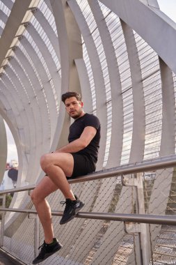 Şehrin korkuluklarında oturan bir adamın görüntüsü.