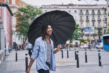 Yağmurdan korunmak için şemsiye altındaki bir adamın portresi. Sakallı ve örgülü bir adam.