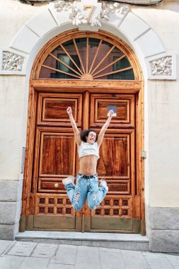 Şehirde zıplayan ve dans eden neşeli adam kadın kıyafetleri giyiyor.