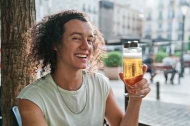 Elinde bira tutan gülümseyen bir adamın portresi..