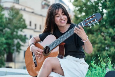 Genç bir Latin şehirde gitar çalıyor. Bir bankta oturan kadın müzik aleti ile pratik yapıyor..