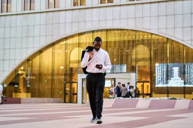 Ofisten akıllı telefonuyla çıkan bir iş adamının tam görüntüsü.