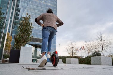 Adam elektrikli scooterıyla yürüyor. İş bölgesinde bir iş adamı
