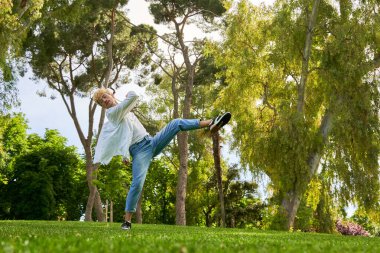 Parkta dans eden sıradan giysili bir adam. Günlük kıyafetlerle çağdaş dans pratiği yapmak..