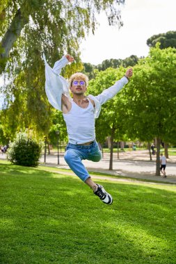 Parkta şehir kostümüyle çağdaş bale yapan genç bir adam..