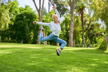 Parkta şehir kostümüyle çağdaş bale yapan genç bir adam..