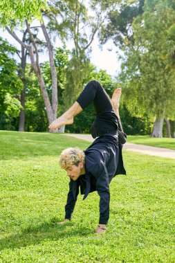 Parkta şehir kostümüyle çağdaş bale yapan genç bir adam..