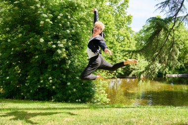 Parkta şehir kostümüyle çağdaş bale yapan genç bir adam..