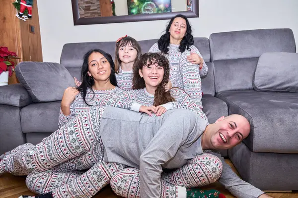 Beş kişilik bir aile pijamalarıyla kanepede oturuyor. Dizlerinin üstünde bir adam ve karnının üstünde bir kadın var. Sahne sıcak ve konforlu, çünkü aile dostluğundan keyif alıyor.