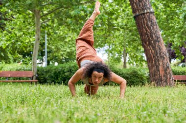 Uzun saçlı bir adam doğanın ortasında çağdaş dans ediyor.