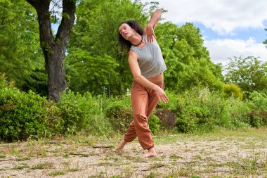 Uzun saçlı bir adam doğanın ortasında çağdaş dans ediyor.