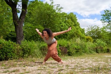 Uzun saçlı bir adam doğanın ortasında çağdaş dans ediyor.