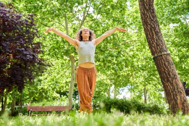 Uzun saçlı bir adam doğanın ortasında çağdaş dans ediyor.